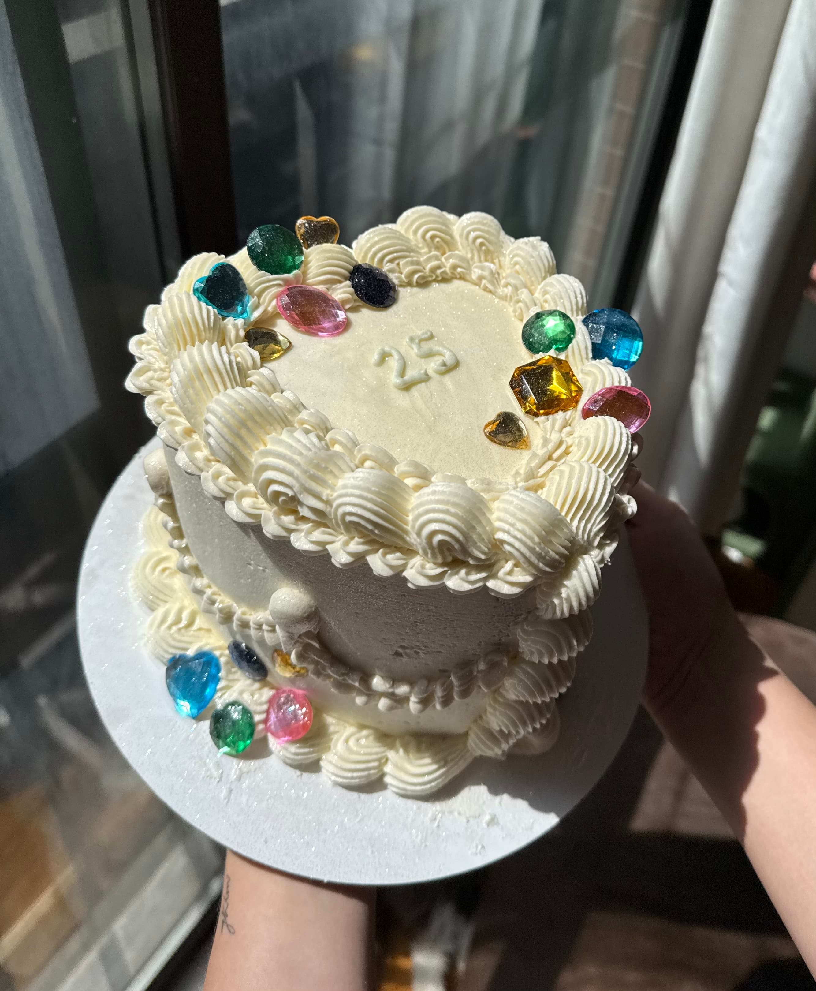 Chocolate cake with raspberry jam and swiss meringue buttercream white heart-shaped 25th birthday cake with vintage piping and colorful candy jewel decorations