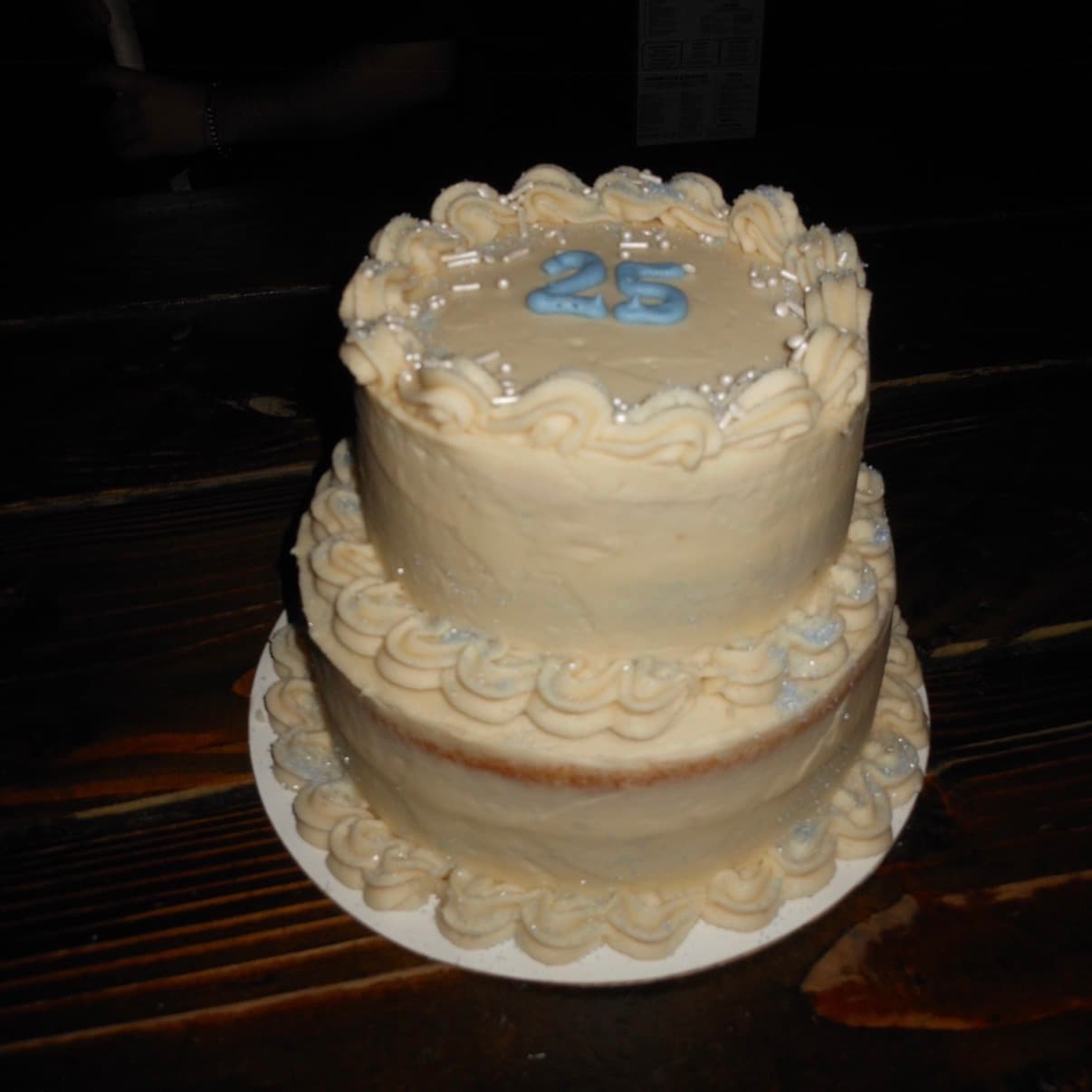 Coconut cake two-tier white buttercream 25th birthday cake with blue "25" lettering and piped shell borders